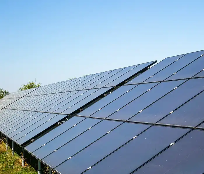 Commercial black solar panels in grass with blue sky